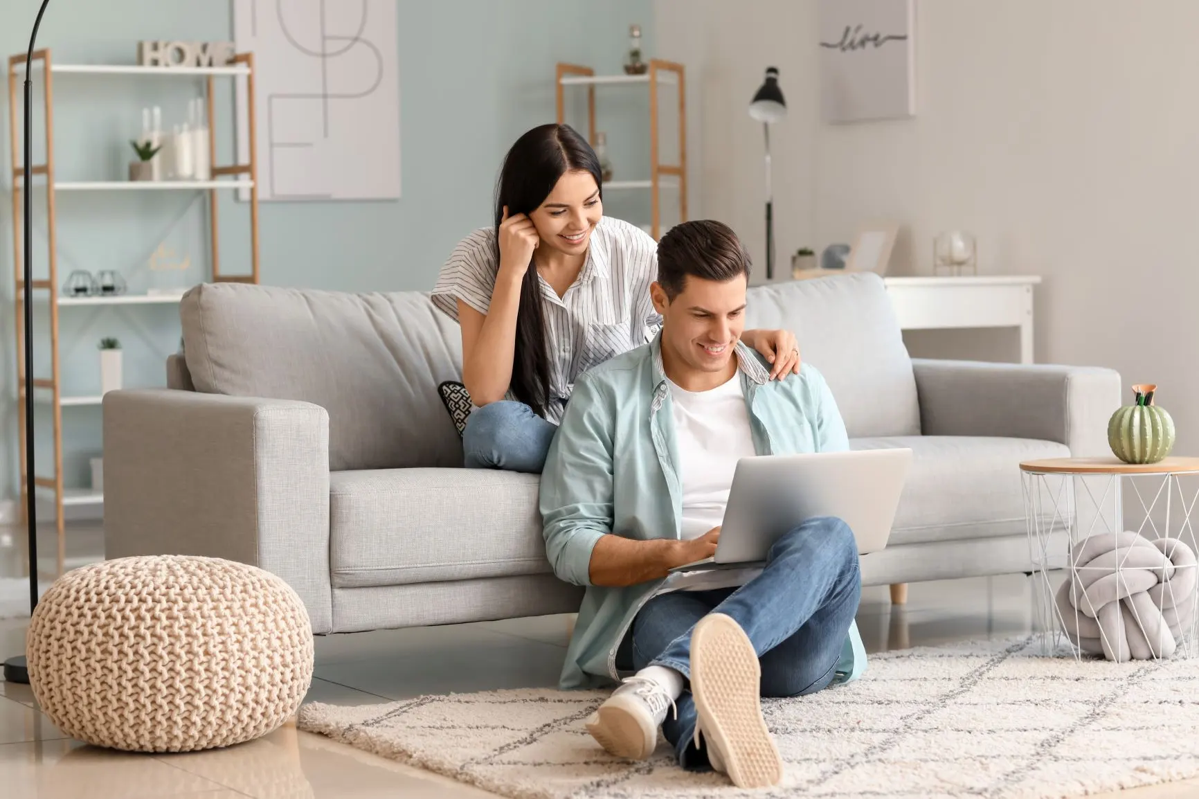 Picture, happy young couple sitting on couch looking at laptop. Texas electricity plans. Smart up your power to choose. EnerWisely is the smart app to compare plans based on your consumption and get cheap electricity. EneWisely smart app, Texpo Energy, Sign up free